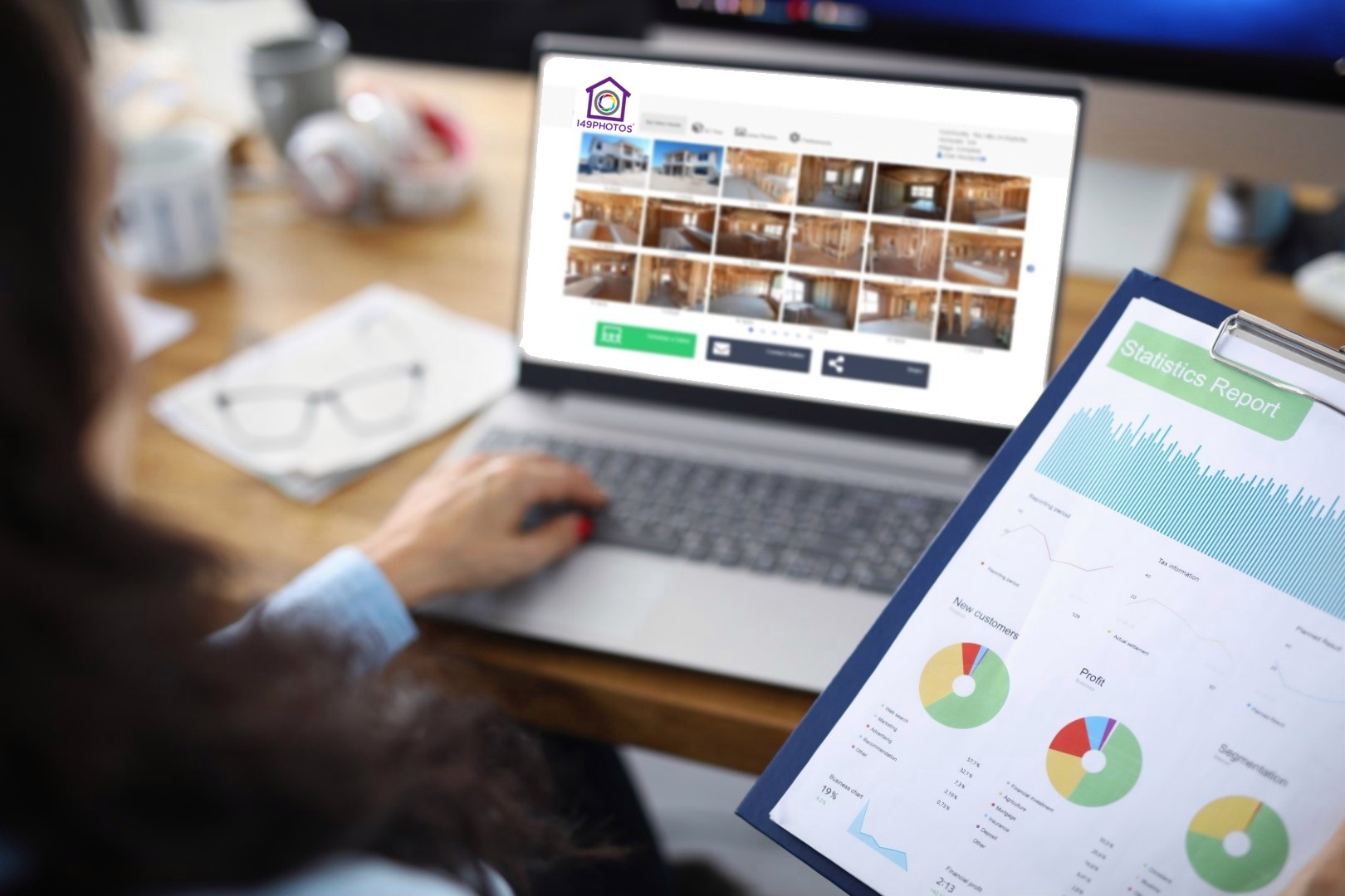 Business woman looking at 149Photos on her laptop computer while holding a sales report